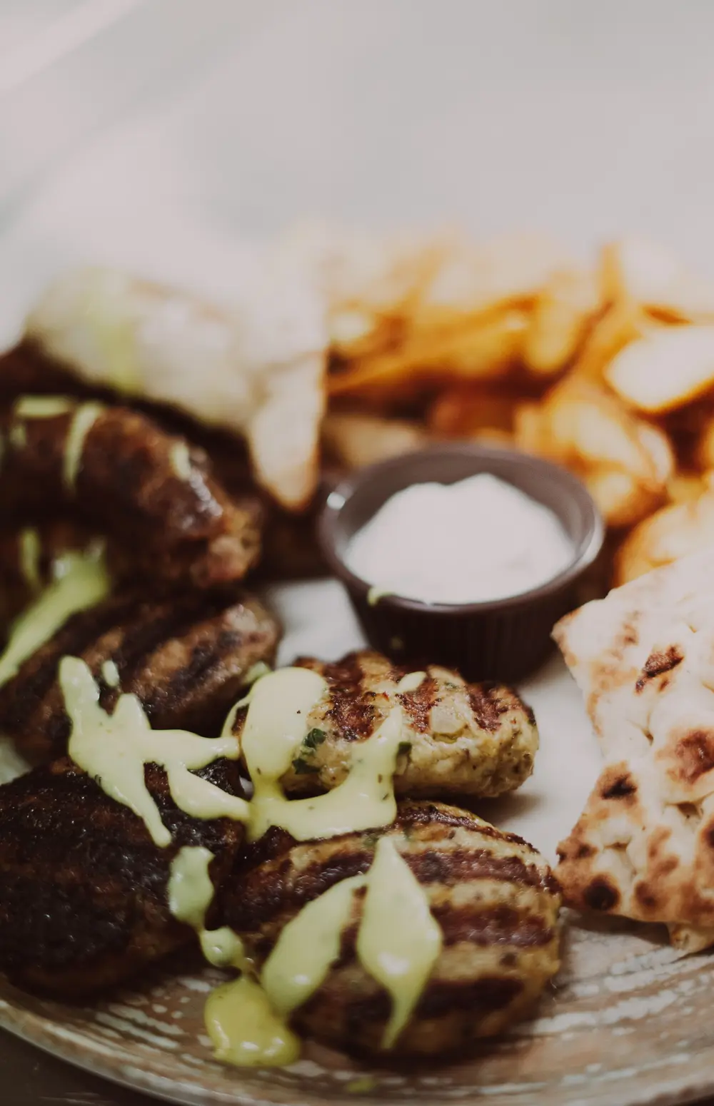 Illustrative Greek-style platter with grilled meat, pitta and a dip